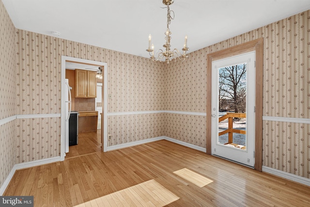 unfurnished dining area with a chandelier and light hardwood / wood-style flooring