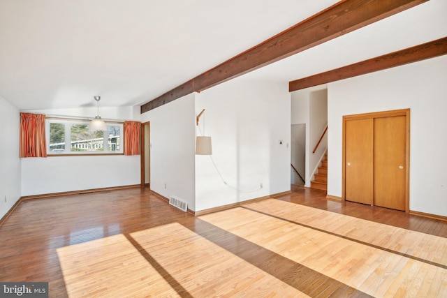 spare room featuring hardwood / wood-style floors and beamed ceiling