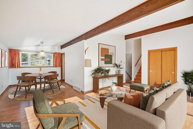 living room featuring beamed ceiling and light hardwood / wood-style flooring