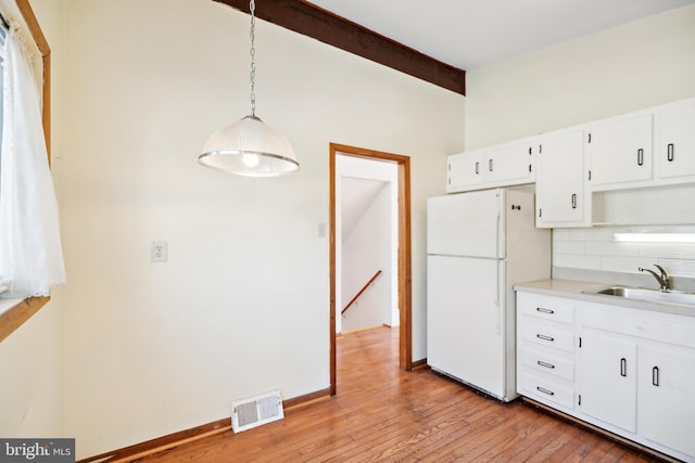 kitchen with tasteful backsplash, sink, white refrigerator, decorative light fixtures, and white cabinetry