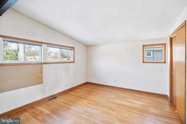 empty room with light wood-type flooring and vaulted ceiling