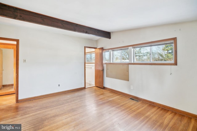 spare room featuring vaulted ceiling with beams and light hardwood / wood-style flooring