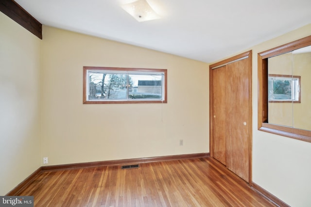 unfurnished room with lofted ceiling and hardwood / wood-style flooring