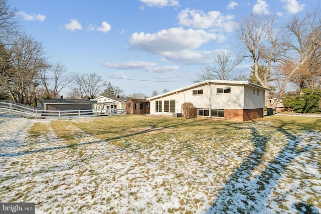 snow covered back of property featuring a lawn