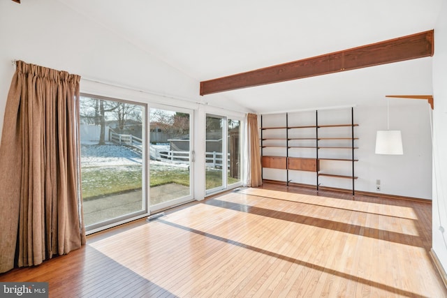 interior space with wood-type flooring and vaulted ceiling with beams