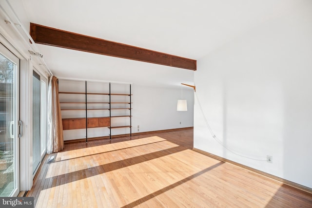 unfurnished room with beam ceiling and hardwood / wood-style flooring