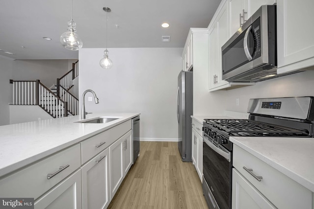 kitchen with white cabinetry, sink, stainless steel appliances, and decorative light fixtures