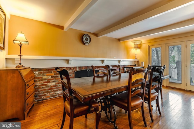 dining area with hardwood / wood-style flooring, beam ceiling, and french doors