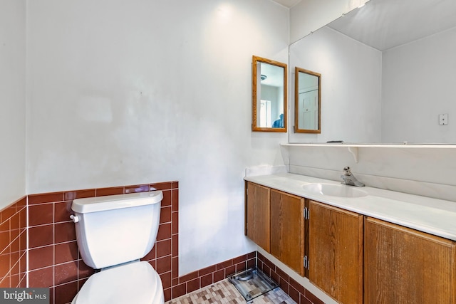 bathroom featuring tile patterned floors, vanity, toilet, and tile walls