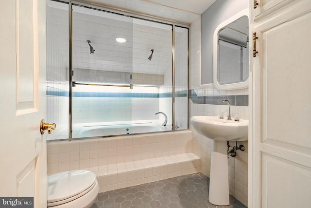 bathroom with tile patterned flooring, toilet, and tile walls