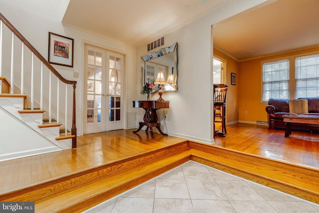 tiled entryway with ornamental molding, a baseboard radiator, and french doors