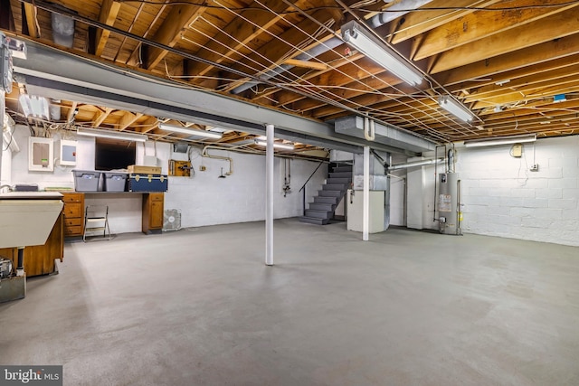 basement featuring sink, electric panel, heating unit, and water heater