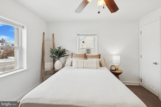 bedroom with multiple windows, ceiling fan, and dark carpet