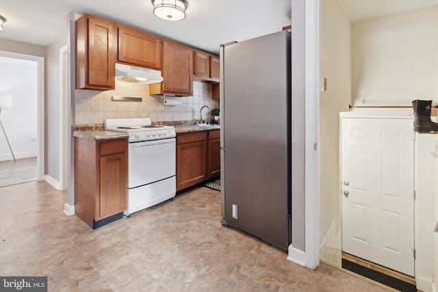 kitchen featuring light stone countertops, sink, backsplash, stainless steel fridge, and white stove