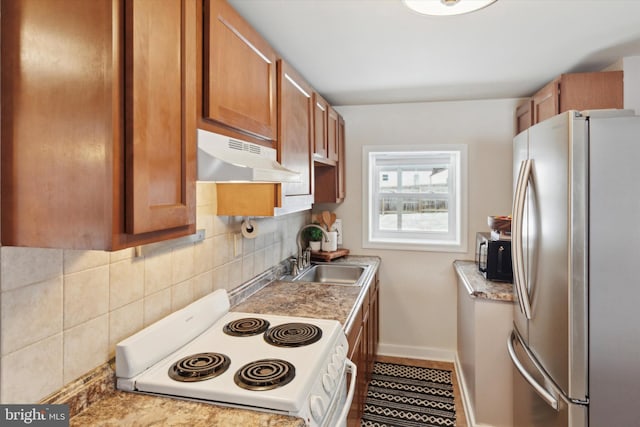 kitchen featuring tasteful backsplash, stainless steel refrigerator, electric range, and sink