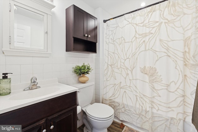 bathroom featuring a shower with shower curtain, vanity, toilet, and tile walls