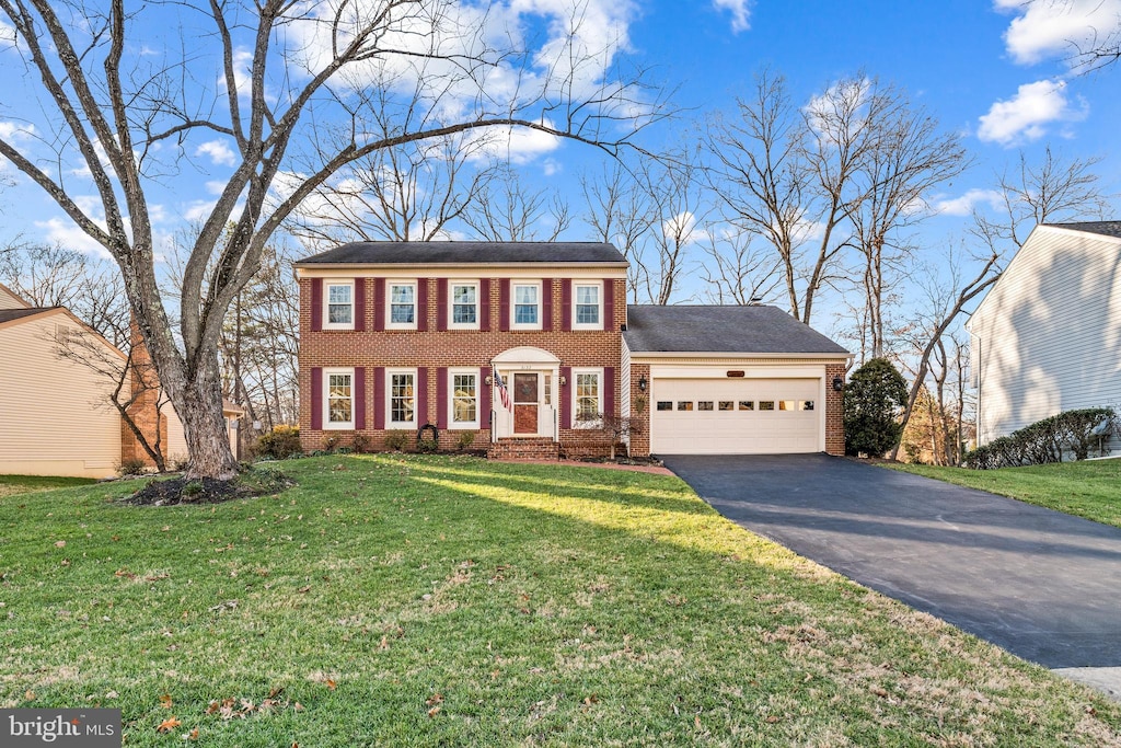 colonial home featuring a front yard and a garage