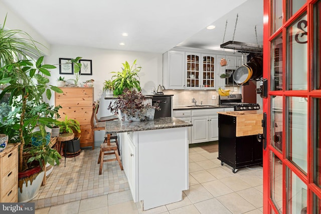 kitchen featuring white cabinetry, tasteful backsplash, stainless steel range oven, a breakfast bar area, and a kitchen island