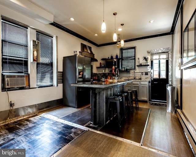 kitchen with appliances with stainless steel finishes, pendant lighting, a baseboard radiator, a center island, and a breakfast bar area