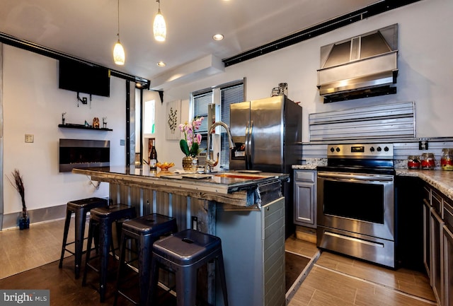 kitchen with electric range, a kitchen breakfast bar, dark stone countertops, decorative light fixtures, and a kitchen island