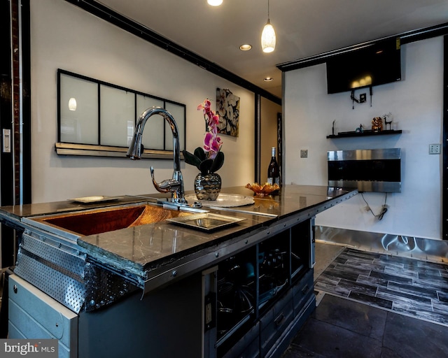 bar featuring sink, dark tile patterned floors, dark stone countertops, crown molding, and pendant lighting