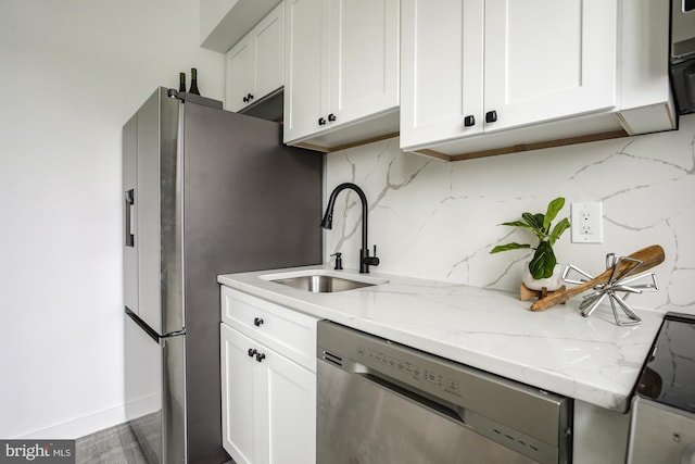 kitchen featuring light stone countertops, stainless steel appliances, white cabinetry, and sink