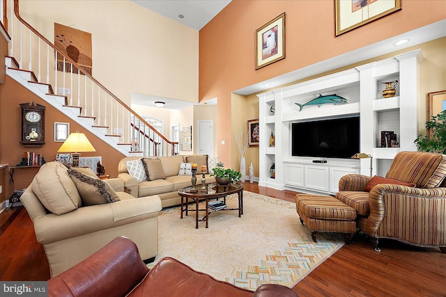 living room featuring a towering ceiling, hardwood / wood-style flooring, and built in features