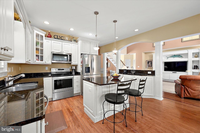 kitchen featuring white cabinetry, sink, a center island, decorative light fixtures, and appliances with stainless steel finishes