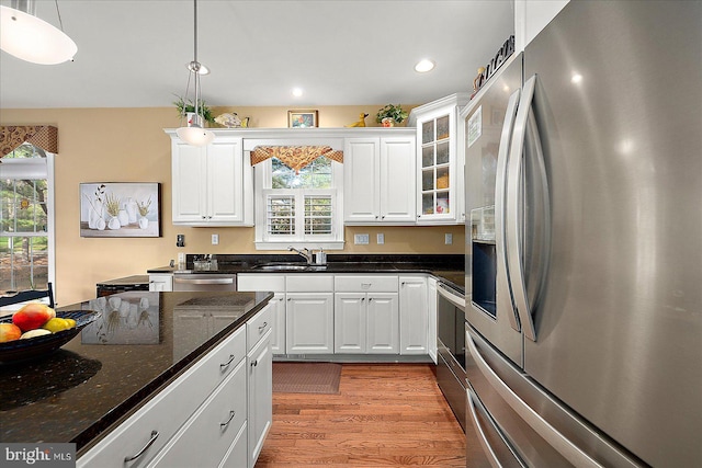 kitchen with stainless steel appliances, sink, decorative light fixtures, dark stone countertops, and white cabinetry