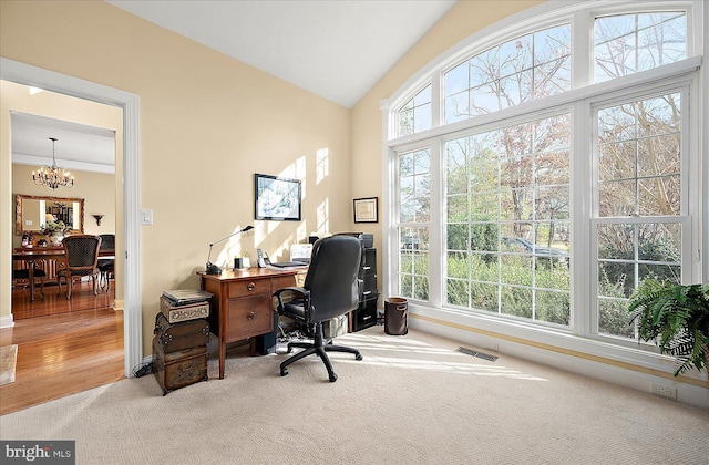 carpeted home office with lofted ceiling, ornamental molding, a wealth of natural light, and a chandelier