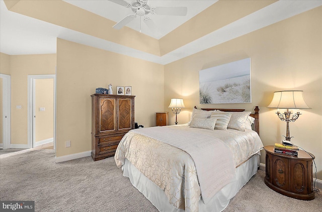 bedroom featuring ceiling fan, a raised ceiling, and light carpet