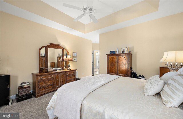 bedroom with ceiling fan, a raised ceiling, and light carpet