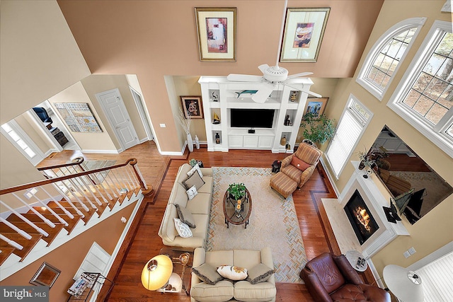 living room featuring a towering ceiling, hardwood / wood-style flooring, and ceiling fan