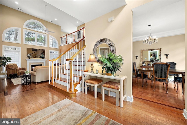 foyer entrance featuring a high ceiling, wood-type flooring, ceiling fan with notable chandelier, and ornamental molding