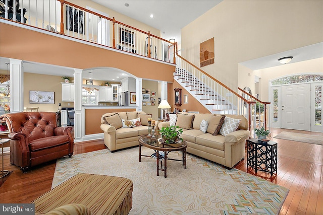 living room with a high ceiling, decorative columns, and light hardwood / wood-style floors