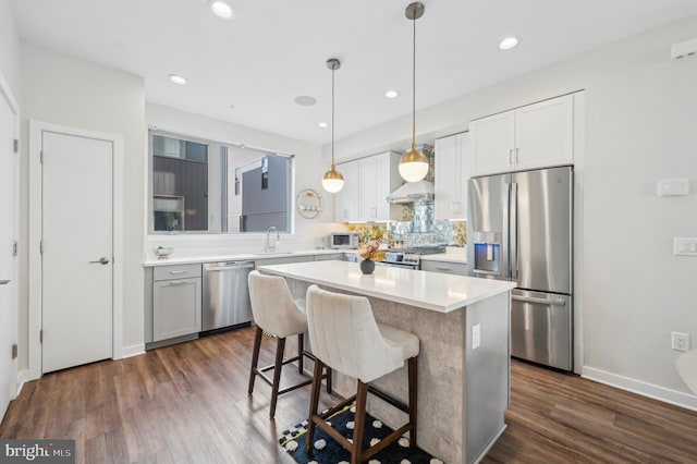 kitchen with white cabinetry, a breakfast bar area, stainless steel appliances, dark hardwood / wood-style flooring, and a kitchen island