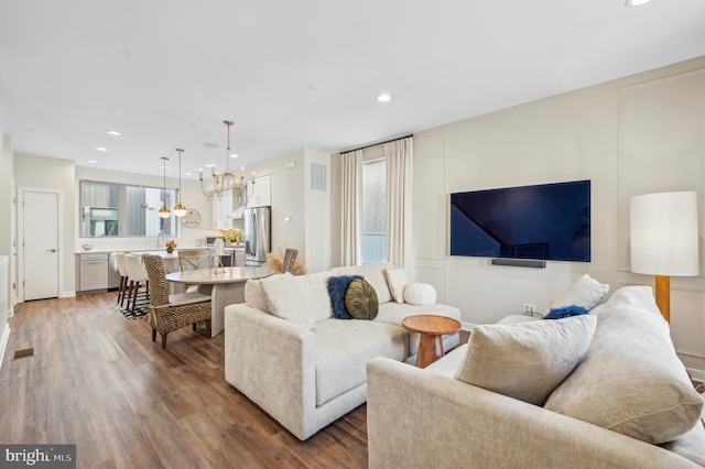 living room with dark hardwood / wood-style flooring, sink, and an inviting chandelier