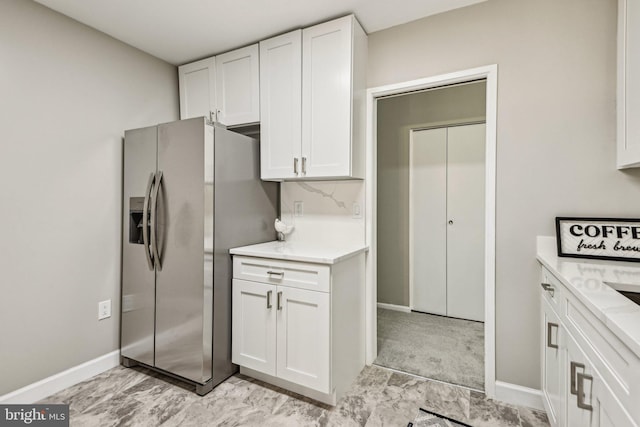 kitchen featuring white cabinets and stainless steel refrigerator with ice dispenser