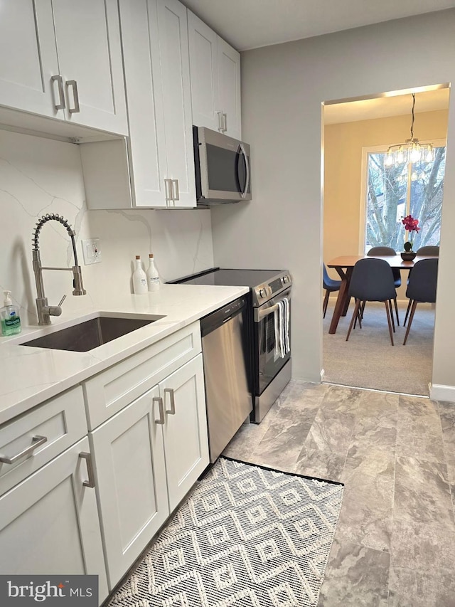 kitchen with white cabinetry, a chandelier, sink, and stainless steel appliances