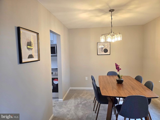 dining area featuring light carpet and a notable chandelier