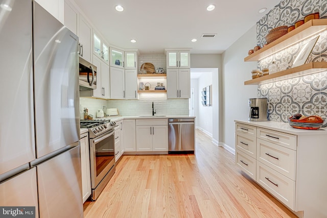 kitchen with light countertops, open shelves, a sink, visible vents, and appliances with stainless steel finishes