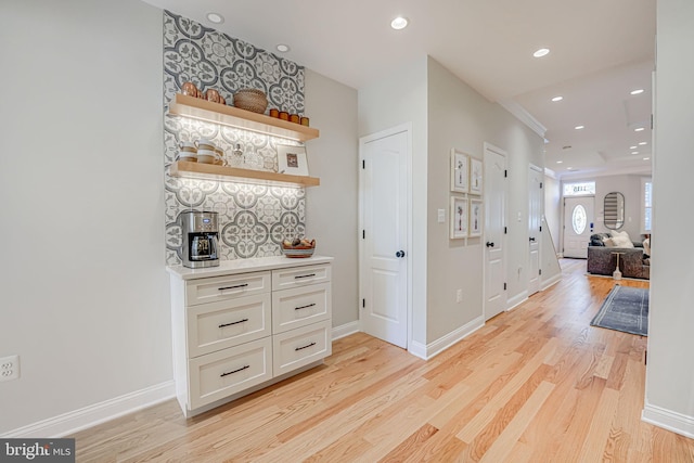corridor with light wood finished floors, baseboards, and recessed lighting