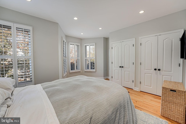 bedroom with multiple closets, light wood-style floors, and recessed lighting