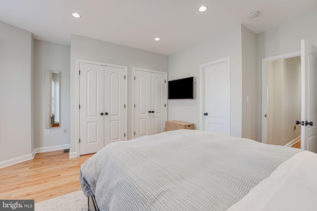bedroom featuring baseboards, multiple closets, recessed lighting, and light wood finished floors