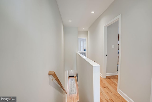 hallway with light wood-style flooring, baseboards, an upstairs landing, and recessed lighting
