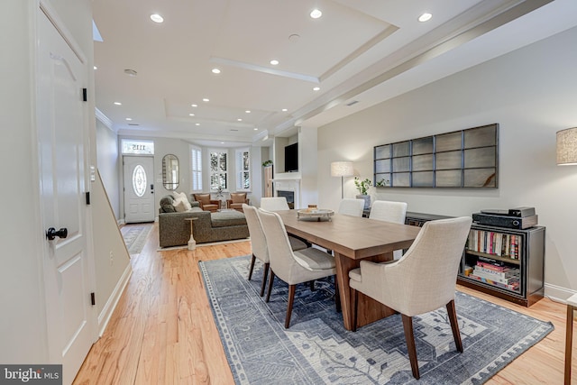 dining area with baseboards, a fireplace, recessed lighting, light wood-style floors, and a tray ceiling