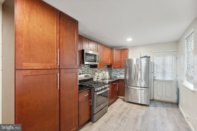 kitchen with tasteful backsplash, light hardwood / wood-style flooring, stainless steel appliances, and sink