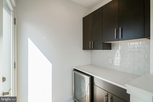 interior space featuring tasteful backsplash, wine cooler, and dark brown cabinetry