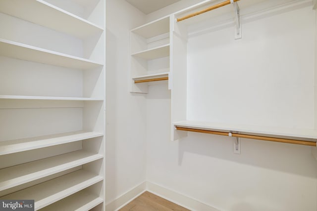 walk in closet with light hardwood / wood-style floors