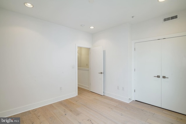 unfurnished bedroom featuring light hardwood / wood-style flooring and a closet